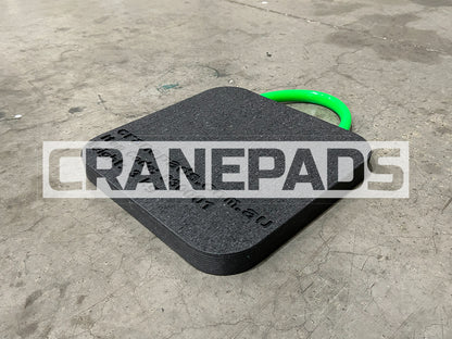 Black crane pad with a green handle on a concrete floor, branded 'CRANEPADS'.