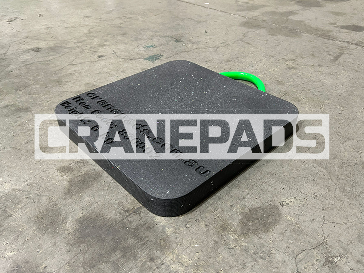 Black crane pad with green handle on a concrete floor, branded 'CRANEPADS'.