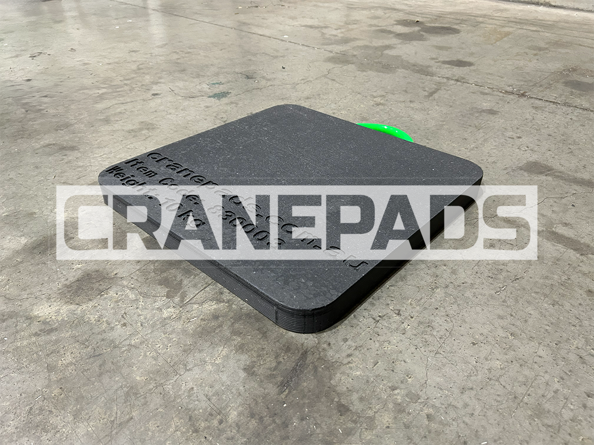Black crane pad on a concrete floor with 'CRANEPADS' branding.