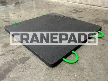 Black crane pad with green corners on a concrete floor, branded 'CRANEPADS'.