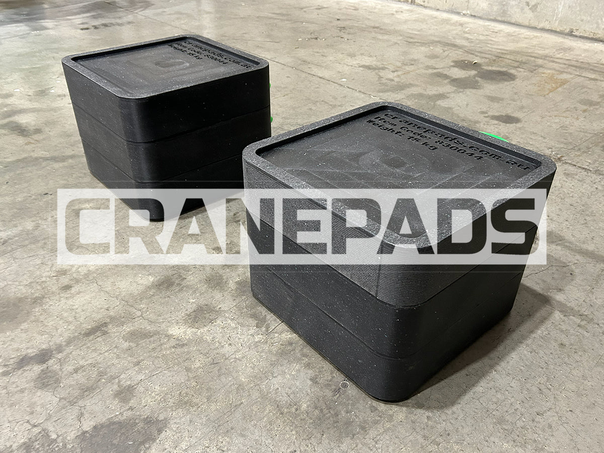 Two black crane pads on a concrete floor with 'CRANEPADS' branding.